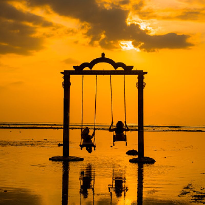 Beautifull Gate with girls swing above ocean sunset. View from Gili island, Trawangan,